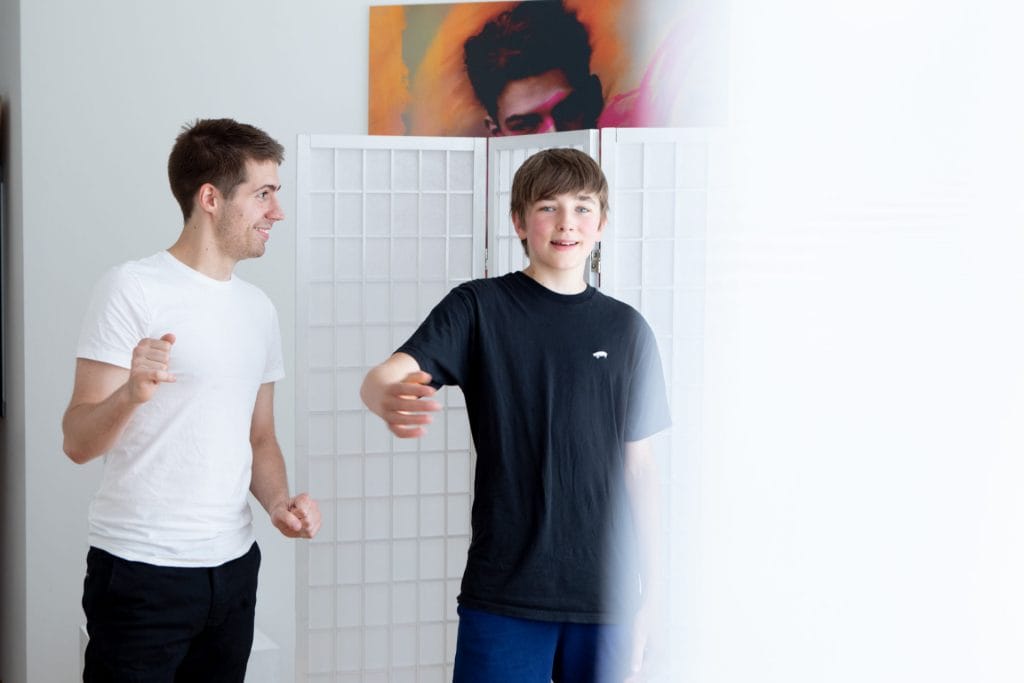 Zwei junge Männer stehen nebeneinander in einem Raum und wollen gerade ein Gespräch beginnen.