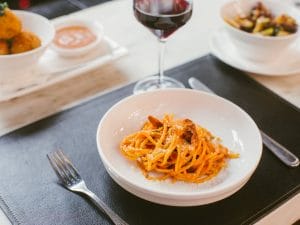 Ein Teller Pasta und ein Glas Wein auf einem Tisch.