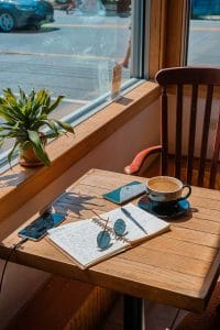 Ein Holztisch mit einer Tasse Kaffee und einem Notizbuch.